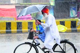 Tender care: An elderly man takes his grand-daughter to school during rains in Amritsar on Thursday