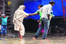 Visitors to the local Civil Hospital wade through a road inundated with rain water at the entrance of the Civil Hospital in Amritsar on Thursday
