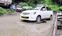 Vehicles cross a potholed road at Lalpani in Shimla