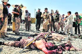 Afghan security forces stand over the bodies of Taliban fighters at the site of a suicide attack in Ghazni on Thursday