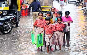 Schoolchildren make their way through a water-clogged street