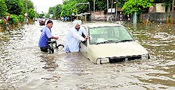 A man pushes his car in a waterlogged road at Power House Road in Bathinda on Friday