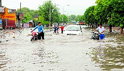 Commuters struggle through a waterlogged road after the region witnessed heavy rain on Friday