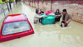 People transport a sick woman in an empty water tank on a flooded street during rain in Srinagar on Friday.