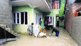 A family tries to remove floodwater from its house in Bemina area in Srinagar.