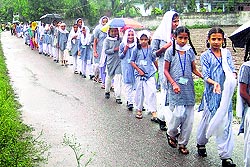 Students brave rain to walk to a temple for the live telecast of the Prime Ministers speech