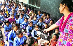 A teacher at a government elementary school in Jalandhar holds a radio as students listen in