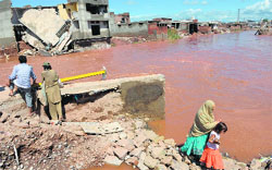 Pakistani residents cross a damaged bridge following flooding in Islamabad on Friday. AFP