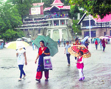 People walk with umbrellas during rain in Shimla on Sunday.