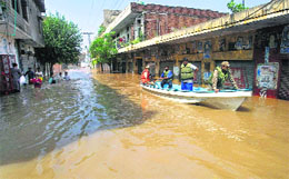 Volunteers use a boat in floodwaters to rescue people in Wazirabad on Sunday
