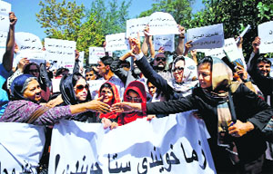 Civil society activists hold banners and posters during a rally against the gang-rape incident, in Kabul on Sunday