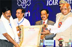 Governor Kaptan Singh Solanki gives an award for professional excellence to dairy entrepreneur Mahesh Chander Chawla in Karnal on Monday. Tribune photo: Ravi Kumar
