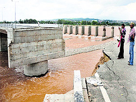 People look at a damaged bridge in Bhagwati Nagar that was swept away by floods in Jammu on Monday.