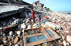 Devastated by deluge, children walk amid the debris of a residential house that was damaged by the floods on the banks of the Tawi river in Jammu