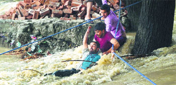 People assist a stranded man with ropes during floods in Srinagar on Tuesday.