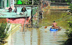 Men await rescue teams on the rooftop of their submerged house in Srinagar on Tuesday