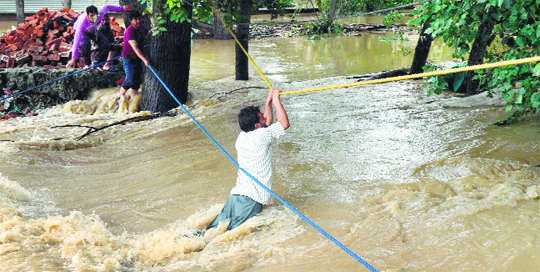 A man uses a rope to make his way across floodwaters in Srinagar. 