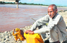Villagers wait on the banks of the Tawi to reach their homes on the outskirts of Jammu. 