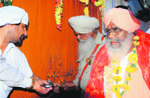 Mahant Baldev Giri along with the warrant officer after taking  possession of the Pathshala in the disputed portion of the ancient Ram Tirath Temple near Amritsar on Wednesday.