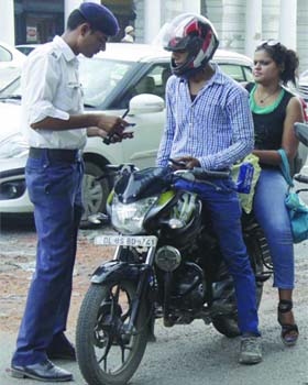 A policeman hands over a traffic violation challan in case of a woman riding pillion without a helmet in the Capital on Wednesday