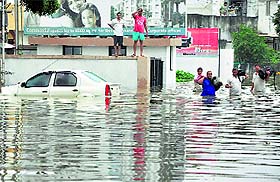 People shift from a flooded locality after heavy rains lashed Vadodara on Wednesday.