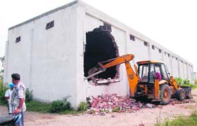 A JCB pulls down a commercial building at Saggar Colony in Jalandhar on Thursday