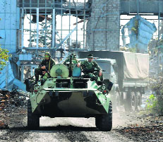 Pro-Russian armoured vehicles drive down the road leading to the destroyed Luhansk Airport, east Ukraine, on Thursday.