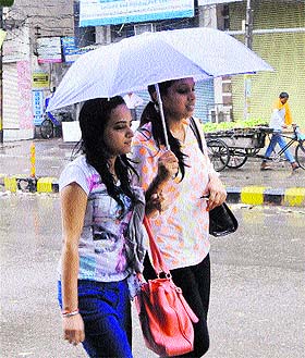 Girls carry an umbrella to protect themselves from the rains in Amritsar on Friday. 