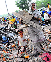 A woman salvages construction material from the debris