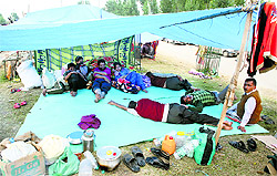 Flood victims rest in a makeshift tent on a road divider in Srinagar on Friday