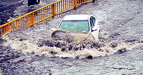 A commuter drives through a waterlogged Domoria bridge road in Ludhiana on Friday.