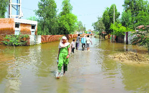 Residents of Panniwala village wade through an inundated street on Friday.