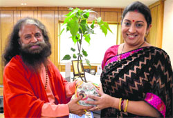 Swami Chidanand Muni hands over a symbolic sapling to Human Resource Development Minister Smriti Irani in New Delhi on Friday. A Tribune photograph