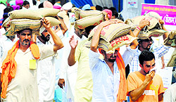 Farmers carry bags of seeds on their heads at Kisan Mela on the PAU campus in Ludhiana