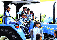 schoolgirls sit on a tractor displayed at the two-day fair in Ludhiana