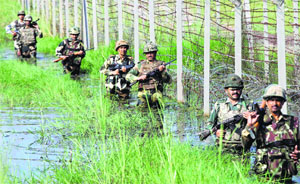 BSF personnel patrol the fenced border with Pakistan as they wade through floodwaters on the outskirts of Jammu.