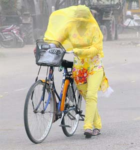 A woman covers her face with her dupatta to save herself from a dust storm in Bathinda on Sunday
