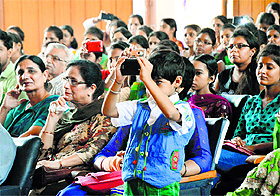 Audience clicks photographs at a function.