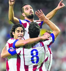 Atletico Madrids Arda Turan (top) celebrates with his teammates after scoring the winner against Real Madrid on Saturday