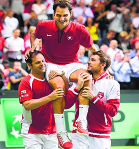 Swiss captain Severin Luethi and Stan Wawrinka carry Roger Federer after winning the Davis Cup semifinal against Italy in Geneva on Sunday