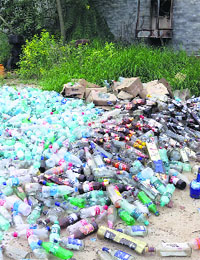 Empty bottles of liquor, soda, cold drinks lie on the rear of an illegal tavern in Muktsar.