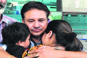 A man hugs his wife and child after they returned from the Kashmir valley at Sri Guru Ramdas Ji International Airport in Amritsar on Tuesday