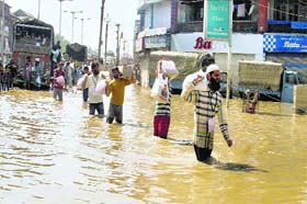 Local volunteers carrying relief wade through a flooded street in Srinagar on Tuesday