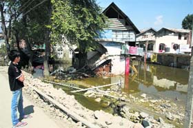 A boy looks at collapsed houses in the Valley