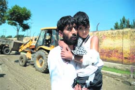 A Kashmiri resident carries his injured son to a hospital in Srinagar