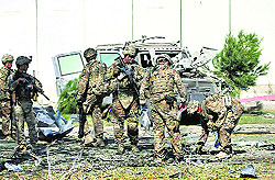 US troops carry out an investigation near a damaged vehicle at the site of an attack in Kabul on Tuesday