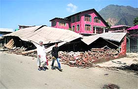 Residents walk past a collapsed house after the floodwater receded in Lasjan near Srinagar.