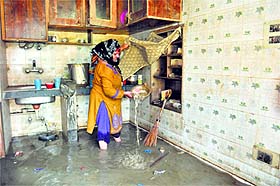 a woman cleans her kitchen as floodwater recedes on the outskirts of Srinagar on Wednesday. 