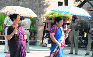 Tourists walk under the shade of an umbrella on a hot summer afternoon in Amritsar on Thursday