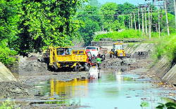 Employees of the Irrigation Department remove silt from a canal in Jammu